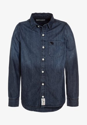 Mørkeblå langærmet denimskjorte med hvide knapper, brystlomme med lille broderet elg og mærke tæt ved kanten.