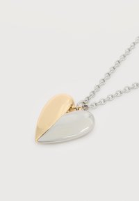Κρεμαστό μισή καρδιά δίχρωμη σε χρυσό και ασήμι, σε ασημένιο αλυσίδα, πάνω σε λευκό φόντο.