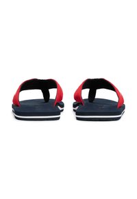 Tongs rouges avec des semelles bleu marine. Sangles texturées avec un design à entre-doigts. Rayure horizontale blanche sur la semelle pour une touche de détail supplémentaire.