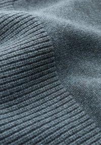 Grau gestrickter Stoff mit einer gerippten Textur, der weiche, pelzige Fasern und subtile Farbvariationen aufweist. Glattes, warmes und dickes Material.