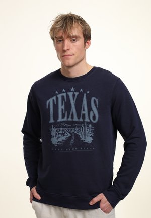 Marineblå sweatshirt lavet af bomuldsblanding med rund hals. Den har et grafisk print af "TEXAS" og ørkenlandskab og inkluderer teksturerede detaljer.