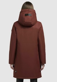 Long, maroon winter coat with a large hood, smooth texture, and a logo patch near the bottom hem. Features a straight silhouette and long sleeves.