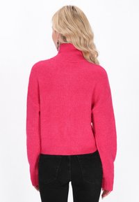 Maglione fucsia lavorato a maglia con colletto alto, spalle scese e maniche lunghe; texture morbida e dettagli a costine; l'orlo arriva alla vita.
