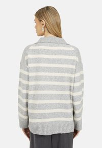 Maglione a strisce grigie e crema con colletto, texture lavorata a maglia e orlo a coste. Vestibilità ampia e dettagli delle cuciture visibili sulle spalle.