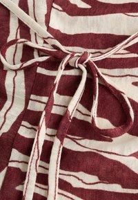 Gros plan sur un nœud attaché sur un tissu à motif rayé abstrait rouge et blanc avec un tissage texturé.