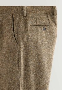 Pantaloni cu model maro, dintr-un material texturat, având plisuri laterale, un buzunar la spate și închidere cu nasture.