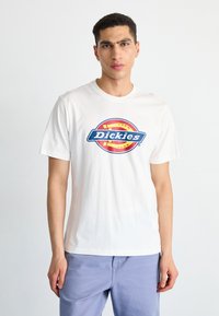 Valkoinen puuvillainen t-paita, jossa on värikäs, pyöreä Dickies-logo. Slim fit -malli, lyhyet hihat ja klassinen pyöreä kaulus.