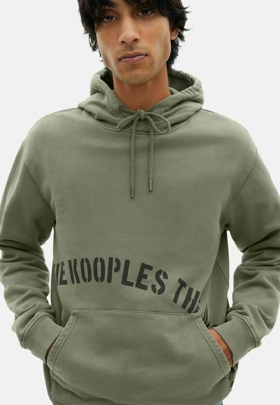 Hoodie vert olive en tissu doux avec une poche kangourou, comportant un texte noir audacieux le long de l'ourlet et une capuche à cordon.