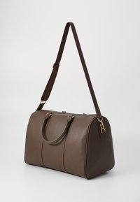 Brown leather duffel bag with dual handles and a detachable strap, featuring gold hardware accents and a rounded shape.