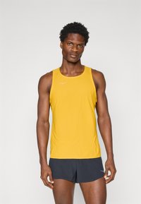 Yellow athletic tank top with a round neckline and a logo on the chest, paired with dark shorts, showcasing a fitted design and smooth texture.