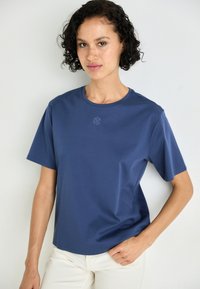 Marineblauw T-shirt met korte mouwen van soepel materiaal met een casual pasvorm. Het heeft een subtiele logo op de borst en een ronde hals.