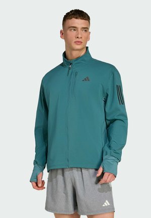 Teal athletic jacket with high collar and full zip. Features three black stripes on the left sleeve and a small logo on the chest.