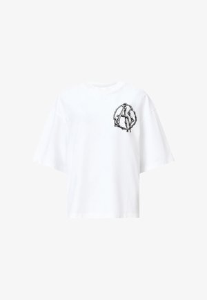 Witte katoenen t-shirt met een oversized pasvorm, korte mouwen en een zwart grafisch ontwerp dat lijkt op een rond embleem op de linkerkant van de borst.