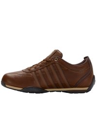 Bruine leren schoenen met een laag profiel, voorzien van zes vetergaatjes, ton sur ton stiksels, drie zijstripes en een zwarte rubberen zool.