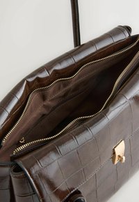 Brown leather handbag with croc pattern, gold hardware, zippered compartments, and a smooth texture. Interior lined in brown fabric.