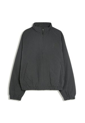 Veste gris foncé zippée avec un motif à carreaux subtil, poignets et taille élastiques, et petit logo brodé sur le côté gauche de la poitrine.