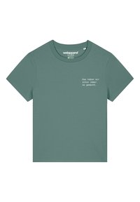 Groene katoenen t-shirt met korte mouwen. Het ontwerp aan de voorkant heeft witte tekst: "Das haben wir schon immer so gemacht." Ronde hals.