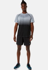 Gray and black short-sleeve athletic shirt with horizontal lines, paired with black shorts and blue running shoes. Lightweight fabric.