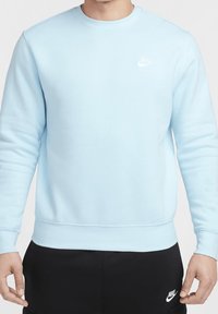 Felpa azzurra a girocollo realizzata in morbido tessuto, con polsini e orlo a costine, e un piccolo logo Nike bianco sul petto.