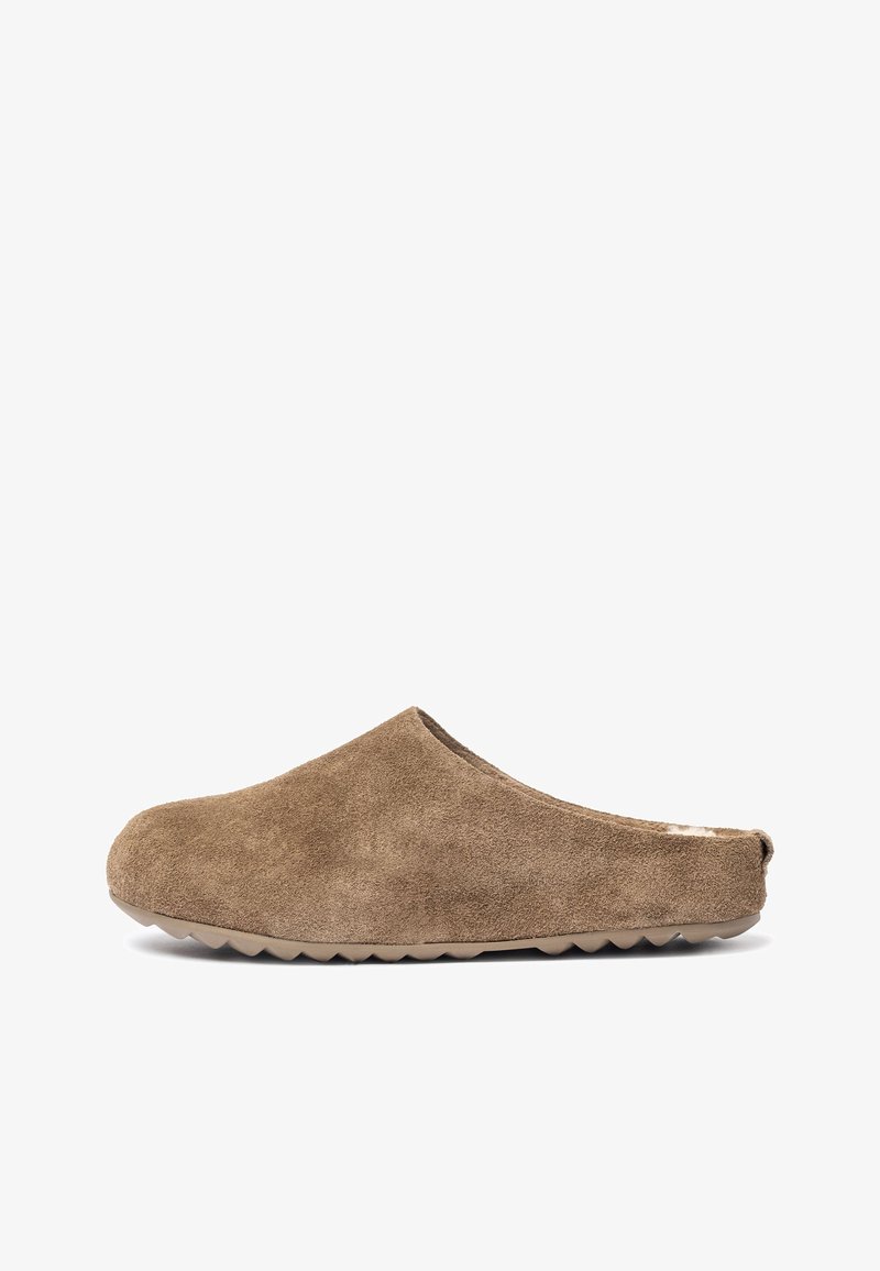 Bruine suede instapper met een afgeronde neus en open achterkant, voorzien van een gestructureerd oppervlak en een dikke rubberen zool met een golfpatroon.