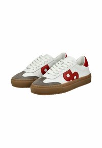 White leather sneakers with red accents, grey suede toe cap, flat laces, and a textured tan rubber sole. Rounded shape, casual design.