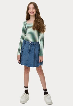 Haut à manches longues rayé vert et blanc associé à une jupe en denim bleu avec un ourlet effiloché et des plis à l'avant. Porté avec des baskets blanches.