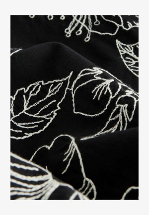Črna tkanina z belimi vezenimi cvetličnimi in listnimi motivi. Šiv omogoča zapletene detajle in teksturiran videz.