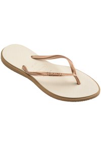 O singură papuc flip-flop bej, cu bretele subțiri metalice aur roz și talpă texturată, ușor înclinat pentru a evidenția detaliile tălpii și ale bretelelor.