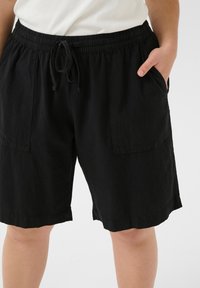 Shorts noirs en tissu léger avec une taille élastique, un cordon de serrage et deux poches latérales. La texture est légèrement froissée.