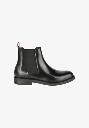 Zwarte leren Chelsea-boot met elastische zijpanelen, ronde neus en een kleine hak. Voorzien van een treklus met rode en blauwe accenten aan de achterkant.