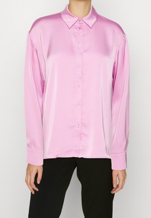 Chemise boutonnée en satin rose clair avec col, manches longues et coupe décontractée ; présente une texture lisse et une fermeture à bouton sur le devant.