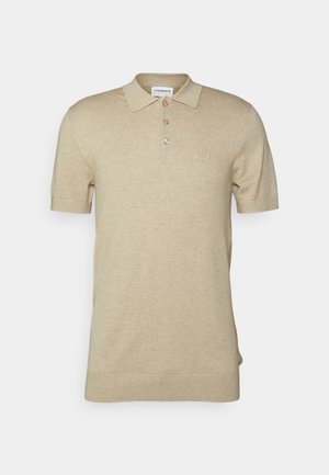 Beige lyhythihainen polo-paita, joka on valmistettu pehmeästä neuleesta. Paidassa on kaulus, kolme ruskeaa nappia ja pieni brodeerattu logo rinnassa.