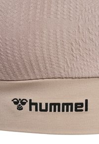 Ljusbeige sportbh med texturerad stickad design och mjuk elastisk rem. Svart "hummel"-logga tryckt på remmen.