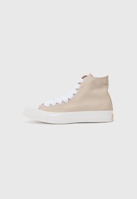 Adidași bej din pânză, cu guler înalt, cu șireturi albe și talpă din cauciuc. Prezintă un finisaj texturat și un design minimalist.