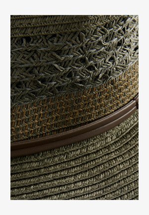 Sombrero de paja verde oliva con un patrón tejido texturizado, que cuenta con una banda de cuero marrón oscuro. Ala ancha con un diseño plano y en capas.