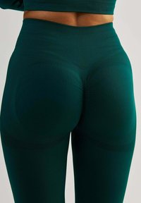 Zielone legginsy o wysokim stanie z prążkowaną teksturą, zaprojektowane jako bielizna kształtująca, z panelem modelującym i gładkim materiałem w okolicy bioder.