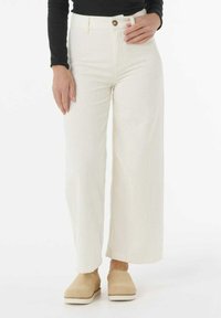 Hvide corduroy bukser med vide ben, der har høj talje, en frontknap og sidelommer. Sæt dem sammen med beige slip-on sko.