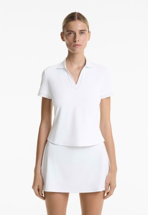 White polo shirt with a V-neck and short sleeves, paired with a matching white skirt, made of smooth, stretchable fabric.