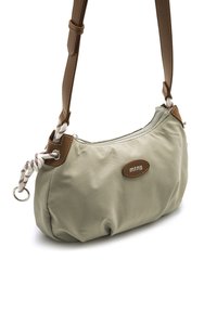 Bolso de tela verde para el hombro con detalles en cuero marrón y una correa de tipo cuerda. Cuenta con cierre de cremallera y un parche circular con el logo.