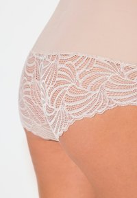 Spitzenunterhose mit einem transparenten, blassrosa Körper und filigranem Blattmuster-Spitzenbesatz entlang der Kanten. Weicher Stoff und elastischer Bund.