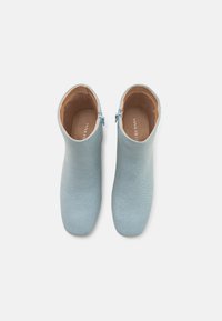 Bottes cheville bleu clair en tissu doux, avec une texture lisse, un bout arrondi et une fermeture éclair sur le côté pour un enfilage facile.
