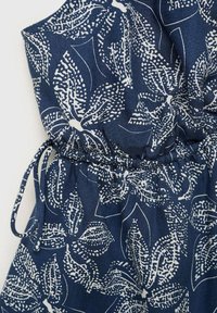 Námořnická modrá overal bez rukávů s bílým listovým vzorem, s elastickým pasem a šňůrkovým detailem pro nastavitelný fit.