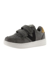 Zapatilla deportiva de cuero gris con acentos de tela negra, que presenta dos correas de velcro, una superficie texturizada y una suela de goma blanca.