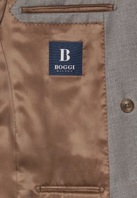Gray suit jacket interior with brown satin lining. Features a navy label with white text reading "BOGGI MILANO" and a button closure.