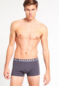 Dunkelgraue Boxerbriefs mit einem weißen "HUGO BOSS" Logo-Bund, aus weichem, elastischem Material. Die Passform ist eng und konturiert.