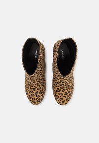 Paire de bottines courtes avec motif léopard et fermetures éclair latérales, doublure intérieure noire, nom de la marque visible à l'intérieur.