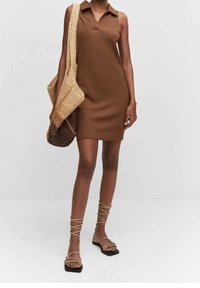 Robe sans manches côtelée marron avec un col, assortie de sandales à lanières et d'un sac fourre-tout tissé dans des teintes claires et foncées.