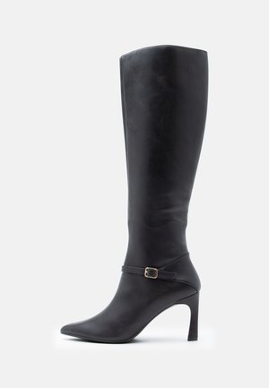 Black knee-high boot made of leather, featuring a pointed toe, stiletto heel, and a decorative ankle strap with a gold buckle.