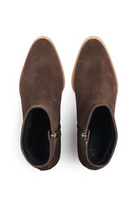 Bottes basses en daim marron avec un bout pointu et des fermetures éclair latérales, présentant une texture lisse et des semelles en caoutchouc couleur camel.