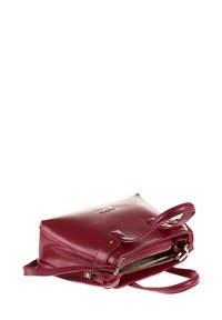 Borsa a mano in pelle rossa con un design minimalista, caratterizzata da doppie maniglie superiori, un compartimento con zip e dettagli in hardware color oro.